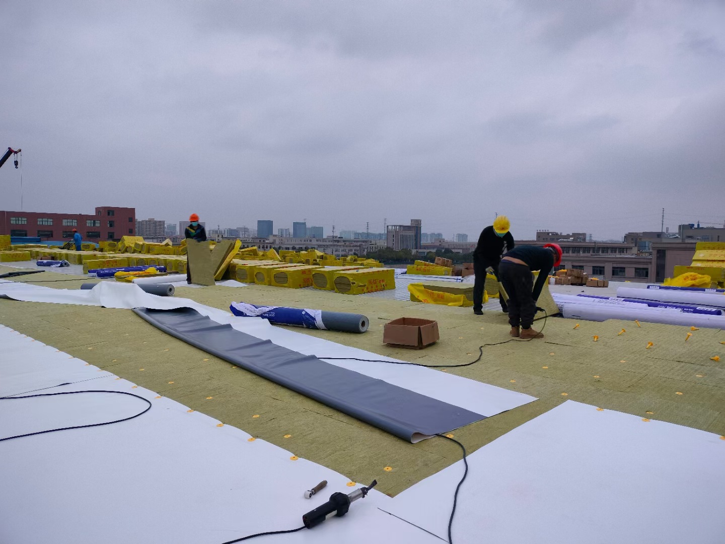 Home Yisosail high-density rock wool boards and TPO waterproofing membrane systems being installed on a large metal roof.